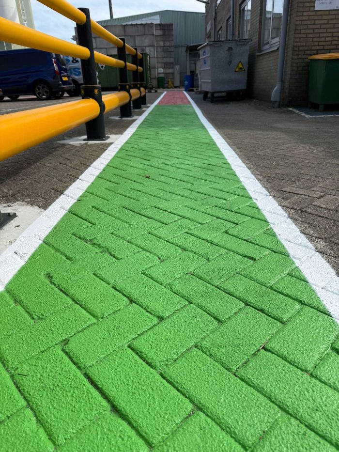 Groen looppad met rood waarschuwingsvlak naast veiligheidsleuningen